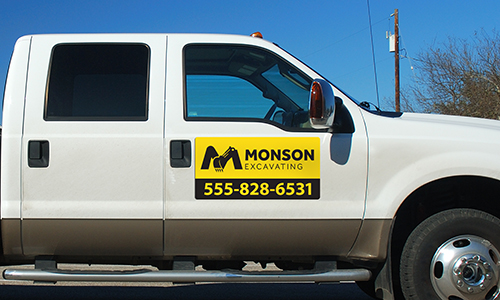 Wholesale Magnetic Sign on a white truck. Magnet is yellow with black words advertising Monson Excavating.